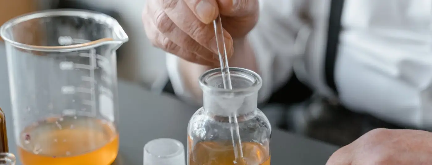 A pipette releasing a drop of fragrance oil into glassware