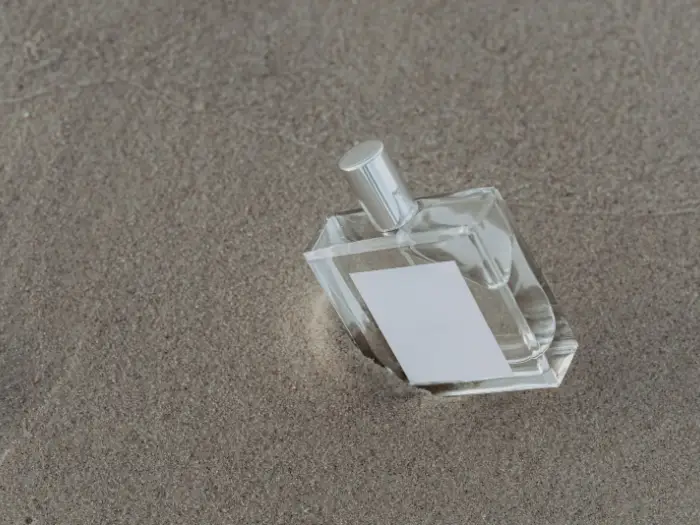 A plain glass fragrance bottle photographed on a neutral surface